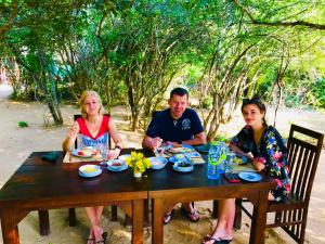 een groep mensen die rond een houten tafel zitten bij Yala Leopard Mobile Camp in Yala