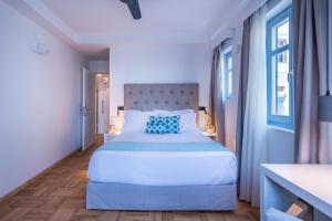 a white bedroom with a large bed with a blue pillow at Shapes Luxury Suites in Ermoupoli +58 photos