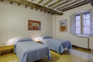 een slaapkamer met 2 bedden en een raam bij Attilio Camere in Siena