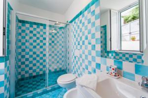 een blauw betegelde badkamer met een toilet en een wastafel bij Villa Vincenzo Di Meglio in Ischia