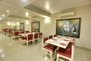 Hotel Sai leela - Shirdi في شيردي: غرفة طعام مع طاولات وكراسي ولوحة
