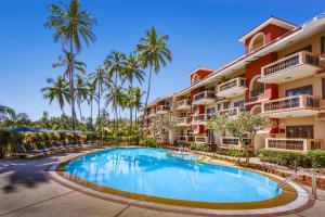 a swimming pool in front of a building with palm trees at Lazy Lagoon, Baga A Lemon Tree Resort, Goa in Baga