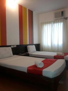 two beds in a room with a colorful striped wall at Travelbee Heritage Inn in Dapitan