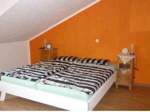 a bed in a room with an orange wall at Land des Friedens in Nettersheim / Eifel in Nettersheim