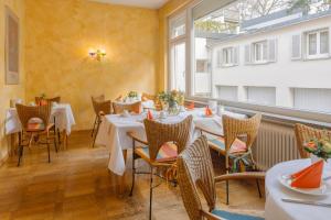 un restaurant avec des tables et des chaises blanches et une fenêtre dans l'établissement Alleehaus, à Fribourg-en-Brisgau
