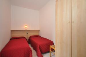 two beds in a small room with red sheets at Condominio Delfino in Bibione