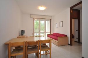 a dining room with a table and a red couch at Condominio Delfino in Bibione