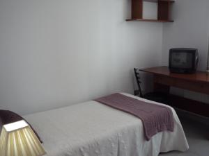 a bedroom with a bed and a desk and a television at Hostal Residencia Ponte Vella in Lugo