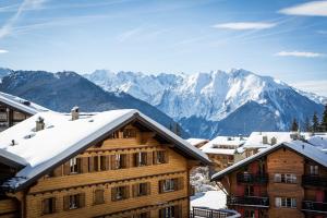 a ski lodge with snow covered mountains in the background at Hotel Farinet in Verbier
