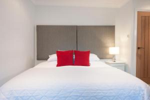 un letto bianco con due cuscini rossi sopra di High Hedges Apartment C a Oxford
