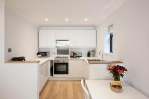 una cucina con armadi bianchi e un tavolo con un vaso di fiori di High Hedges Apartment C a Oxford