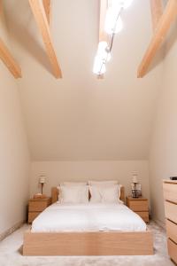 プロイェシュティにあるLacul Verde Resortのベッドルーム1室(白いシーツと木製の天井が備わるベッド1台付)