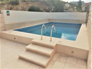 a swimming pool with two metal handles on a patio at Apartmani Marija in Duće