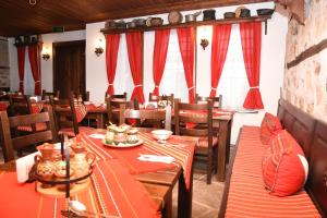 uma sala de jantar com mesas de madeira e cortinas vermelhas em Djudjeva Kyshta Hotel em Panagyurishte