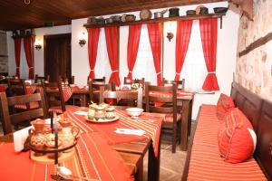 a dining room with wooden tables and red curtains at Djudjeva Kyshta Hotel in Panagyurishte