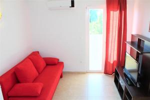 a red couch in a living room with a television at Apartmani Marija in Duće