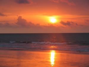 a sunset on a beach with the ocean at Hotel Puerto Gaviota in Tonsupa