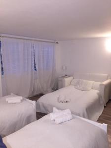 two beds in a room with white walls at Circuito de Aragon. House up to 16 pax in Valdealgorfa