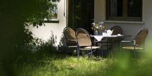 une table avec trois chaises et une table avec des fleurs. dans l'établissement Demeterhof Dünninger, à Hofheim in Unterfranken