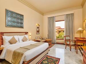 um quarto com uma cama, uma secretária e uma janela em The Ummed Jodhpur Palace Resort & Spa em Jodhpur
