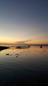 einen Sonnenuntergang über einem Wasserkörper mit einem Pier in der Unterkunft Hotel Ocean in Lahad Datu