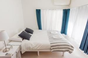 um quarto branco com uma cama com cortinas azuis em Gracias Arakawa - Great Access to UENO & ASAKUSA area em Tóquio
