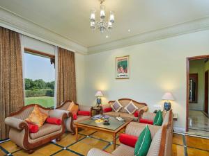 a living room with furniture and a large window at The Ummed Jodhpur Palace Resort & Spa in Jodhpur