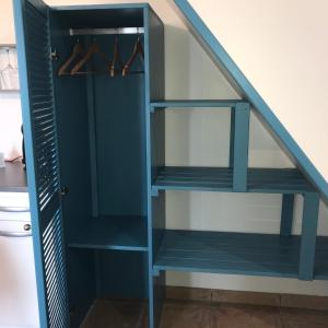 ein blaues Bücherregal unter der Treppe in der Unterkunft Ti Kaz Ravinala in Bois dʼOlive