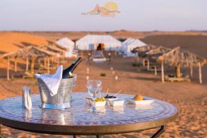 einen Tisch in der Wüste mit Speisen und Getränken darauf in der Unterkunft Erg Chebbi Camp in Merzouga