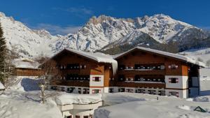 ein Gebäude im Schnee mit Bergen im Hintergrund in der Unterkunft Marco Polo Alpina Familien- & Sporthotel in Maria Alm am Steinernen Meer