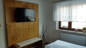 a bedroom with a flat screen tv on a wooden wall at Ferienhaus Günther in Aue