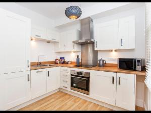 cocina con armarios blancos, fregadero y microondas en Apartment 5 Blue Bridge Court en York