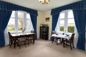 a dining room with blue curtains and a table and chairs at Newcourt Barton in Cullompton