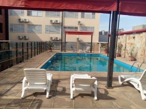 a swimming pool with two lawn chairs and a pair at Hotel Le Park in San Miguel de Tucumán