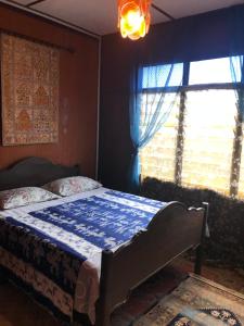 a bedroom with a bed with a blue comforter and a window at Rumah Tiang 16 in Kampong Ulu Jepai