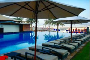 a row of lounge chairs with umbrellas next to a swimming pool at Stunning 5* 4BR-Oceanfront-Apartment in Dubai