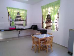 a dining room with a table and chairs and windows at Jerantut Homestay 2 in Jerantut
