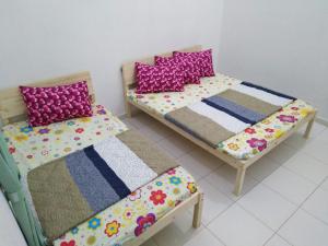 two beds in a room with pink and purple pillows at Jerantut Homestay 2 in Jerantut