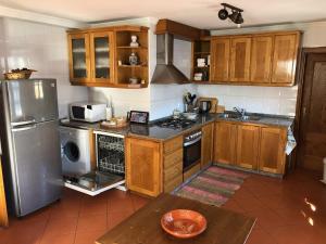 eine Küche mit Holzschränken und einem Edelstahlkühlschrank in der Unterkunft Casa da Ponte Rio de Onor in Bragança