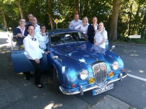 a group of people standing next to a blue car at Hotel Marienhof Baumberge in Nottuln