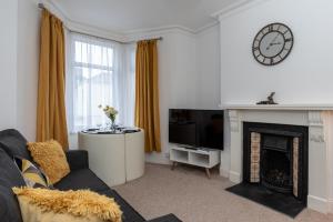 a living room with a fireplace and a clock on the wall at Milton House in Plymouth