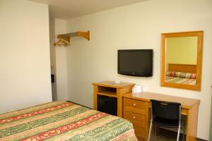 Schlafzimmer mit einem Bett, einem Schreibtisch und einem TV in der Unterkunft King's Rest Motel in Gilroy