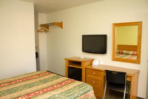 a bedroom with a bed and a desk and a television at King's Rest Motel in Gilroy