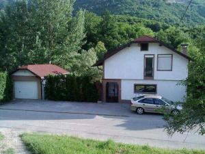 a white house with a car parked in the driveway at Guest House Majstorovic in Banja Luka