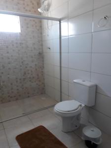 y baño blanco con aseo y ducha. en Pousada da Família en Araranguá