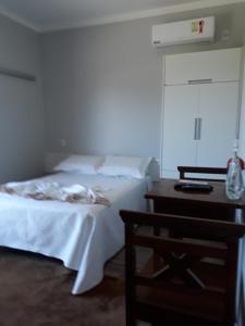 um quarto com uma cama e uma mesa com uma mesa de cabeceira em Pousada da Família em Araranguá