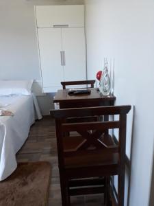 um quarto com uma cama e uma secretária de madeira com uma cadeira em Pousada da Família em Araranguá