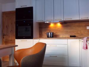 a kitchen with white cabinets and a table and a chair at Residence Alba Montis in Bad Kleinkirchheim