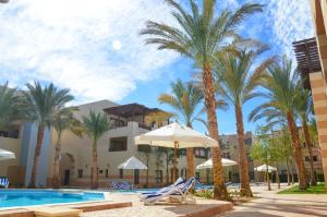 a resort with palm trees and chairs and a swimming pool at Port Ghalib Marina Residence Suites in Port Ghalib