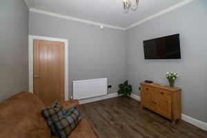 a living room with a couch and a flat screen tv at Am Meadhan - Comet Apartments in Helensburgh